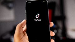 一只手拿着手机显示TikTok标志和品牌。