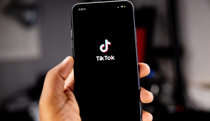 一只手拿着显示TikTok标志和品牌的手机。