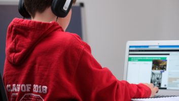 年轻的学生戴着耳机在电脑工作。数字化学习
