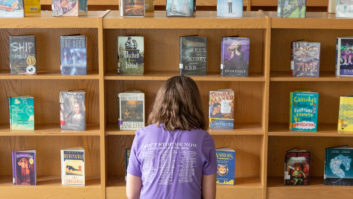 后面的学生看着图书馆书架上满是书。为学习恢复文章。