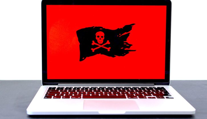 笔记本电脑与黑色头骨和交叉骨在教育网络安全文章红色背景