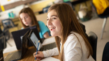 为一篇关于学生选择的文章，一名微笑的中学女学生与其他学生坐在桌子旁