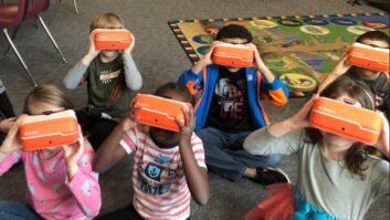 弗吉尼亚的几个小学学生从萨勒姆城市学校使用虚拟现实眼镜坐在教室地板上。