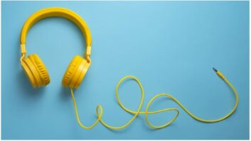 亮黄色的耳机,有线电视在淡蓝色背景文章舒适edtech工具