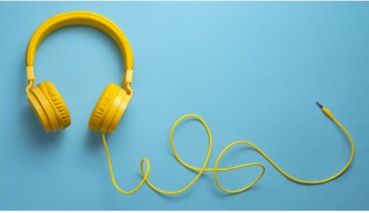 亮黄色耳机和电缆在浅蓝色背景的文章上舒适的教育技术工具