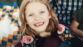 红头发的年轻女孩拿着两朵花微笑的图片，用于缺乏语言病理学家的文章