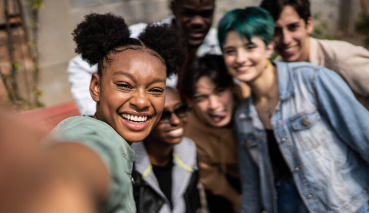 年轻的黑人妇女带着selfies朋友在街上文章在高等教育健康计划
