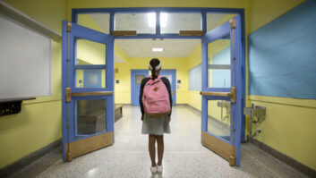 后视图的11岁女孩学校走廊上寻找关于学校安全的文章