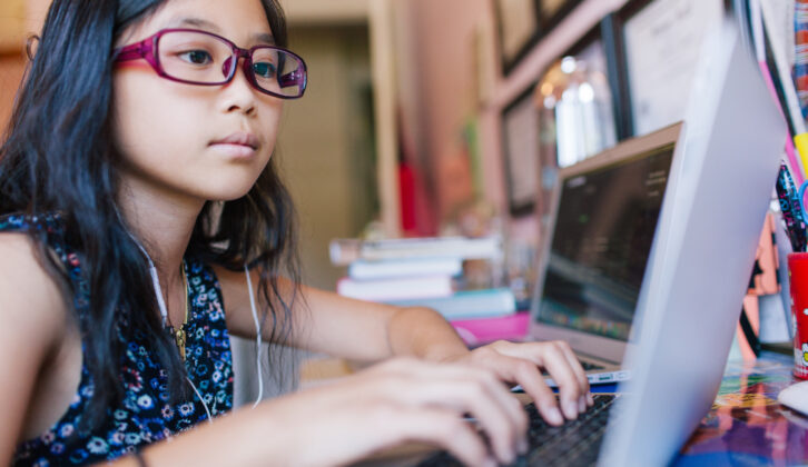 戴眼镜的小女孩打字笔记本在桌子上对虚拟学习文章